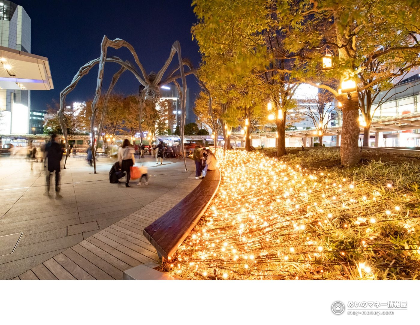 Giant spider sculpture in 66 Plaza at night with gold-lit plantings around it