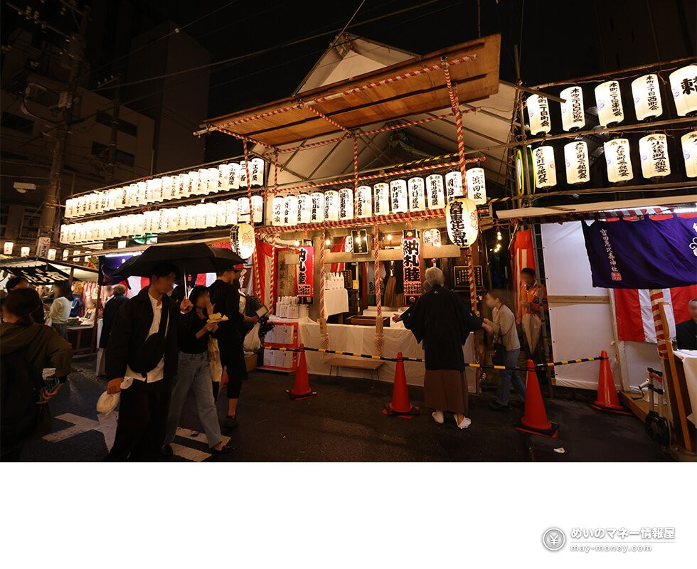 Shrine hall and lanterns at night with visitors holding umbrellas on the street