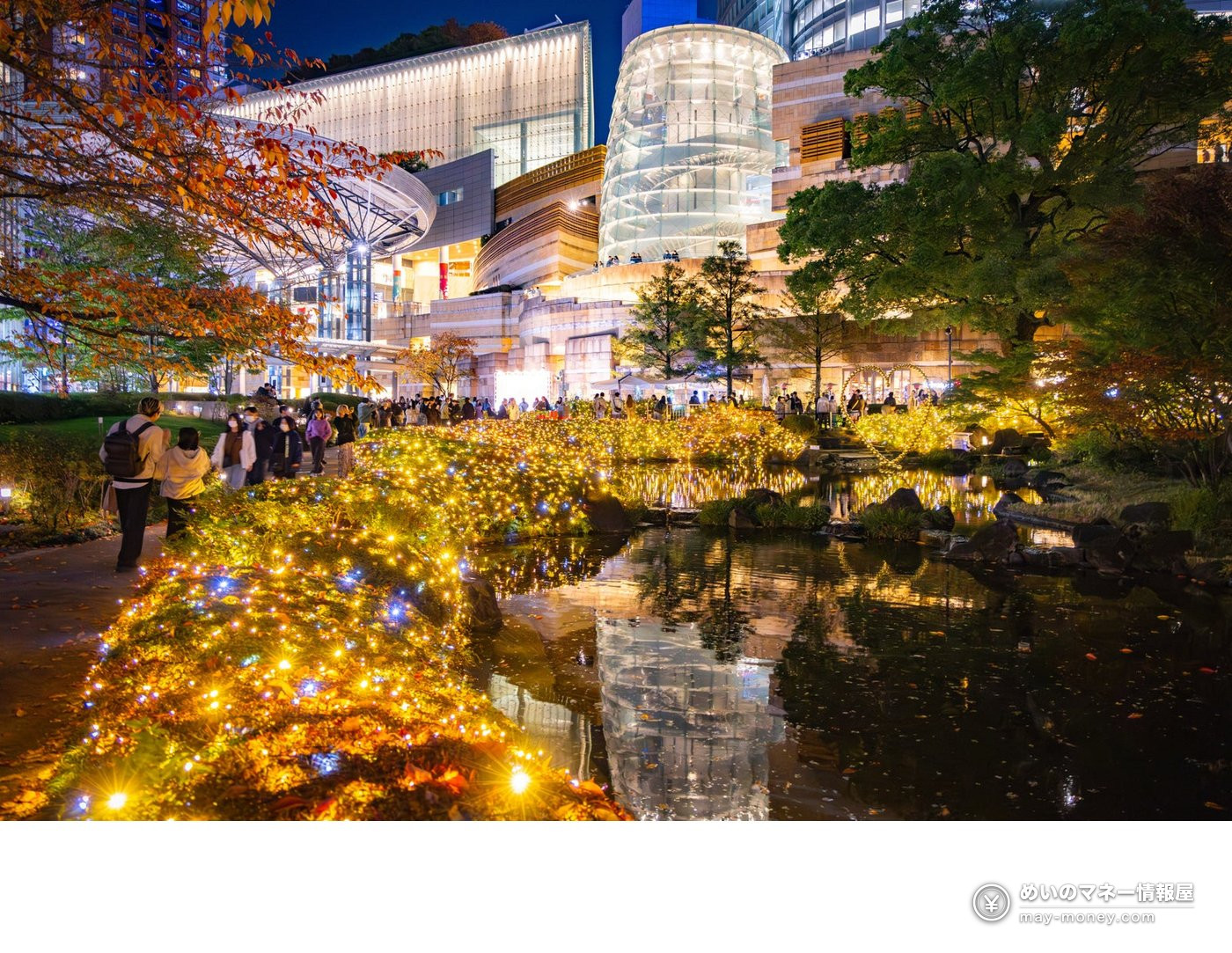 Yellow lights glowing beside the pond in Mohri Garden at night with people strolling