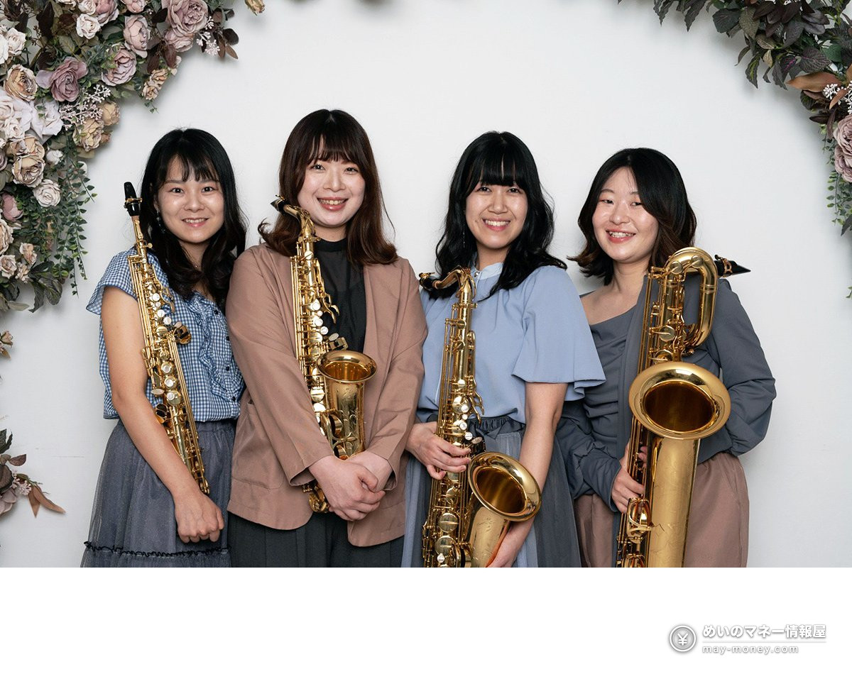 四位手持萨克斯的女性站在花墙前