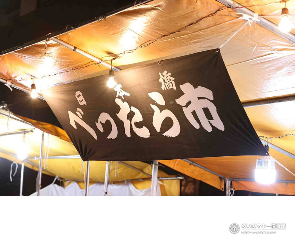 Black banner hung at a stall reading Nihonbashi Bettara-ichi