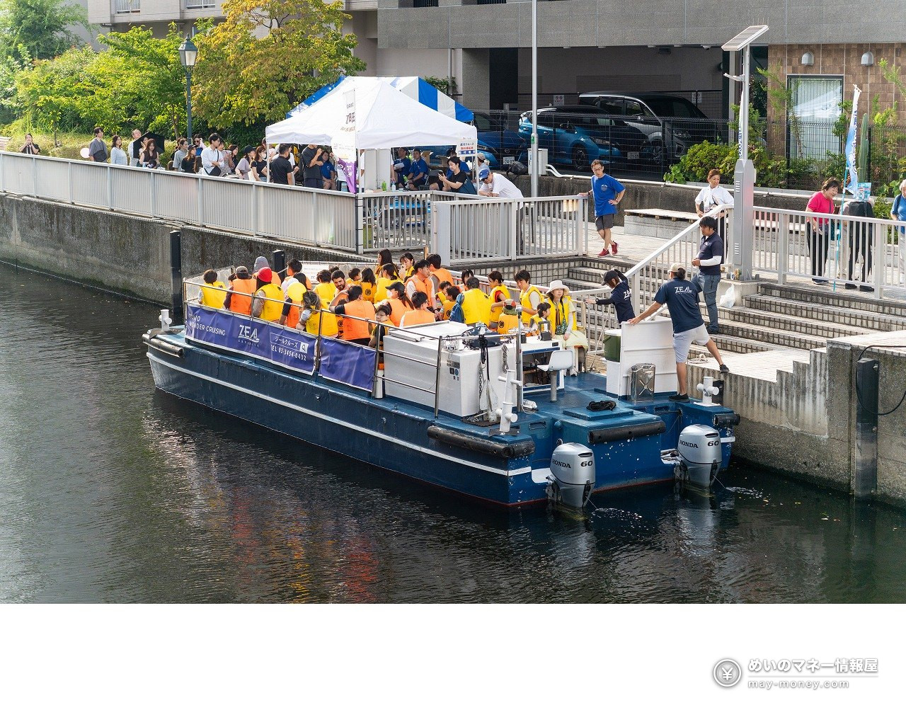 Shibaura Canal Festival 2026: Free Canal Cruise Times & Tips 2 A canal cruise boat full of passengers in life jackets pulling away from the pier under Shinshiba Bridge