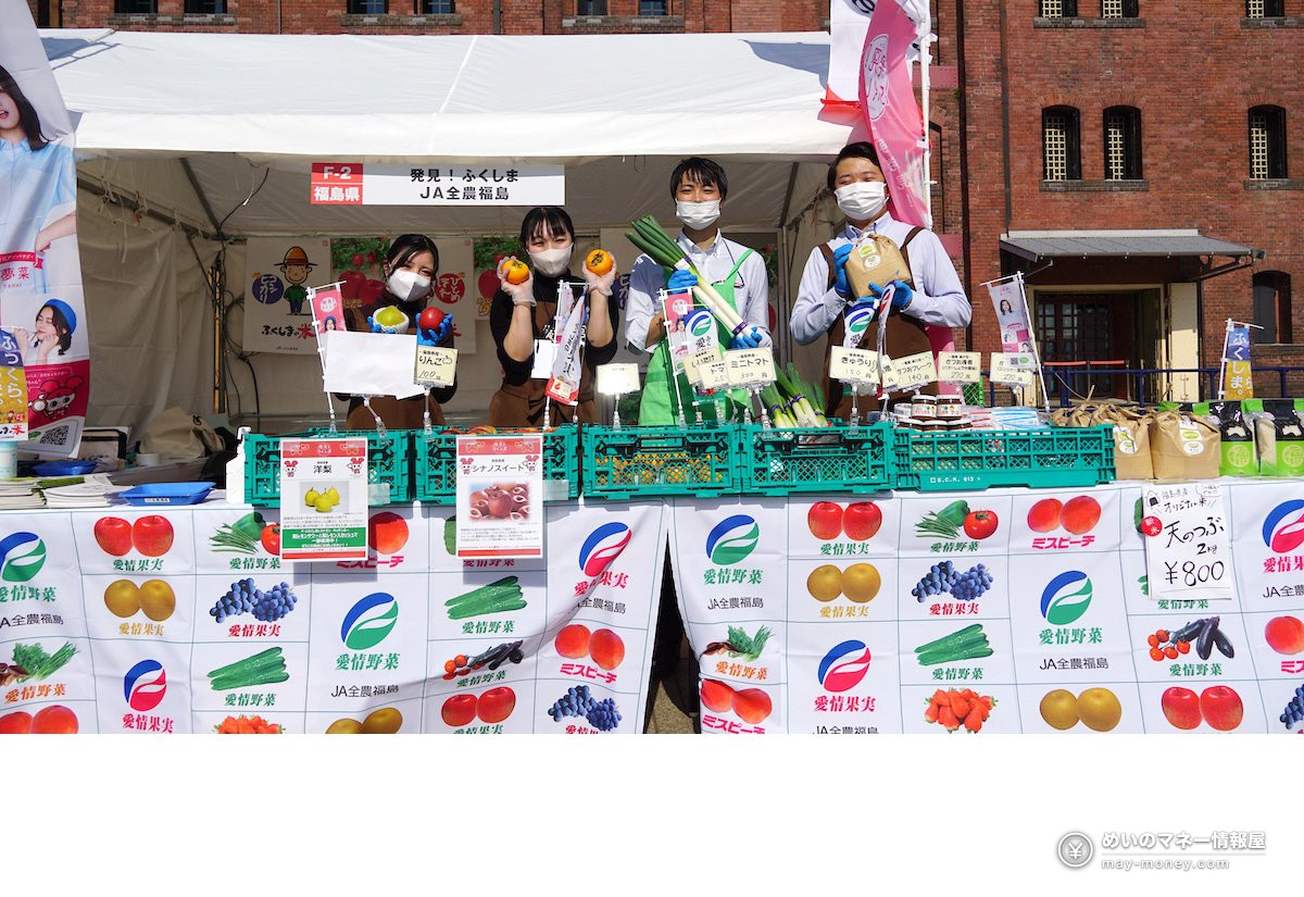 テントの下で野菜や果物を掲げるJA全農福島のスタッフ4人