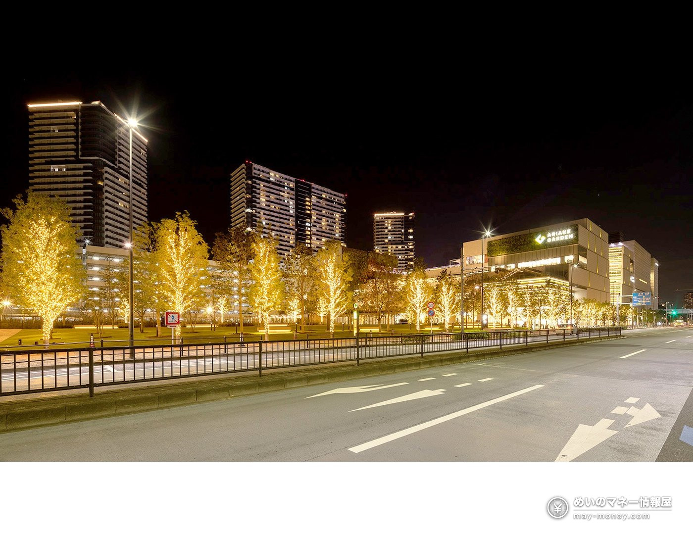 夜晚道路旁点灯的行道树和高楼、商业设施
