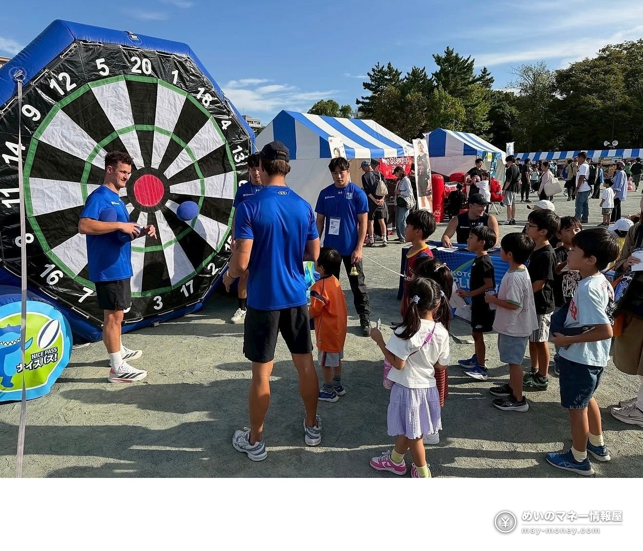Players and children playing in front of a giant dart target at an event