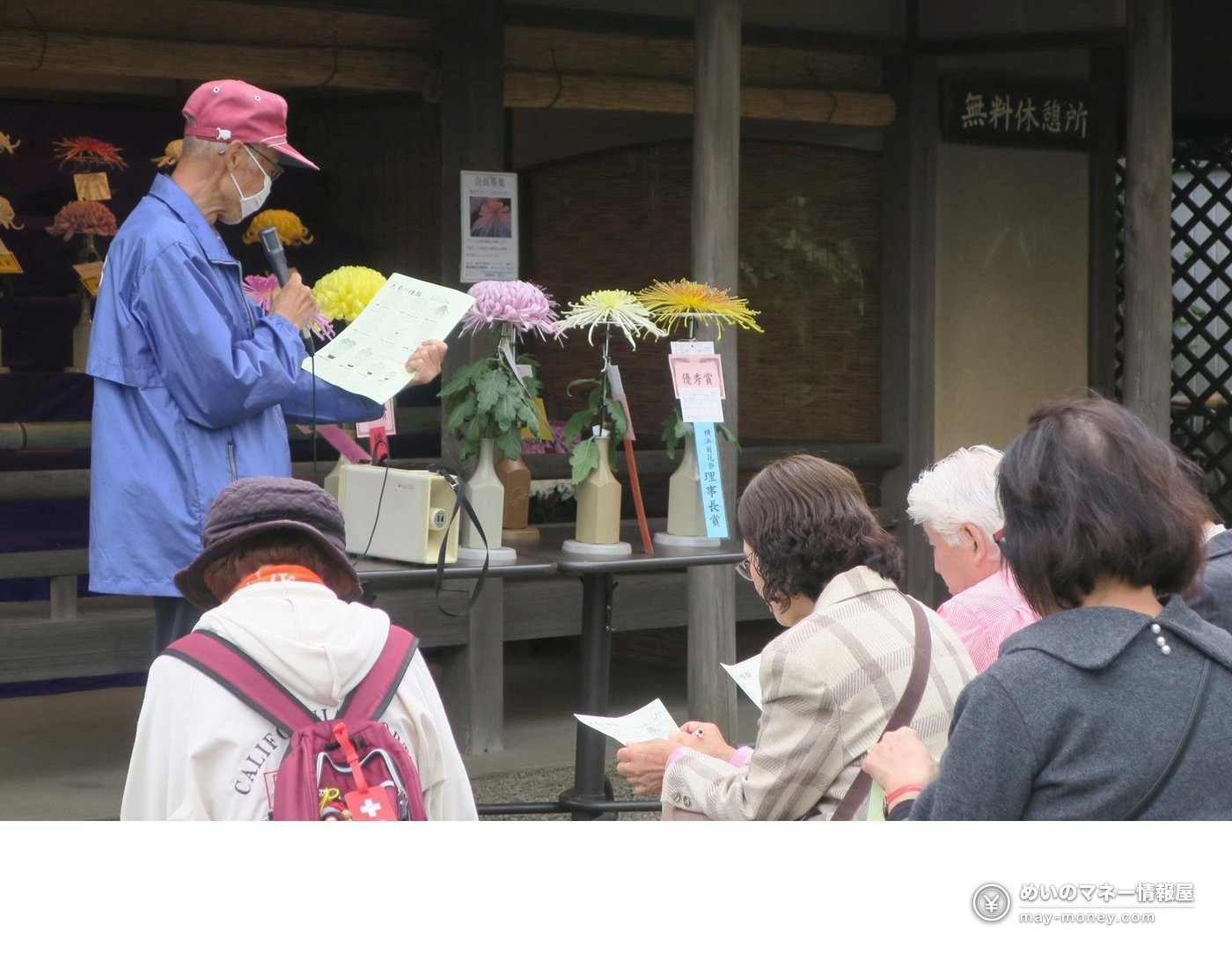 A man explaining chrysanthemums with a microphone to a group of visitors
