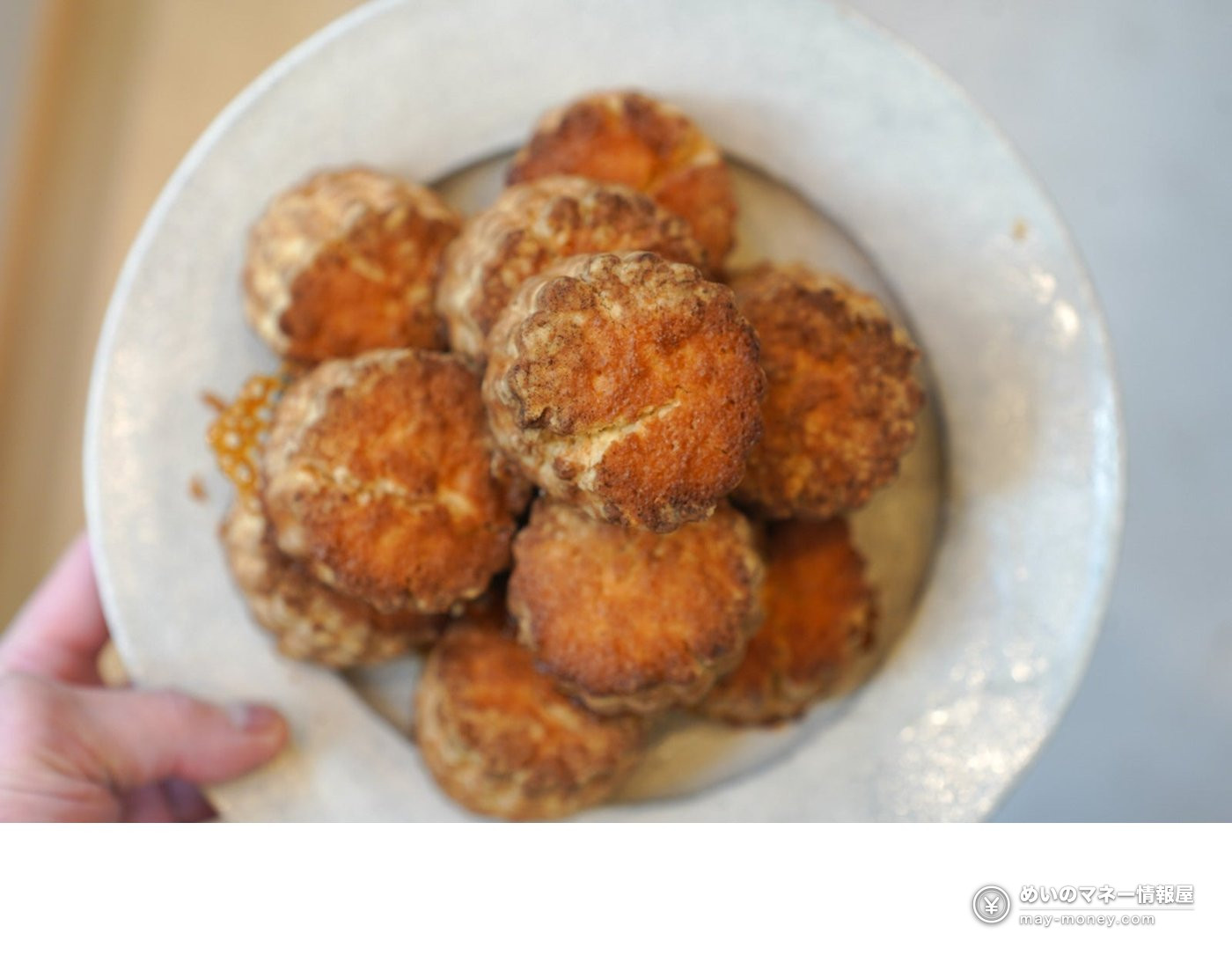 皿に盛った小ぶりの焼き菓子を手に持っている様子