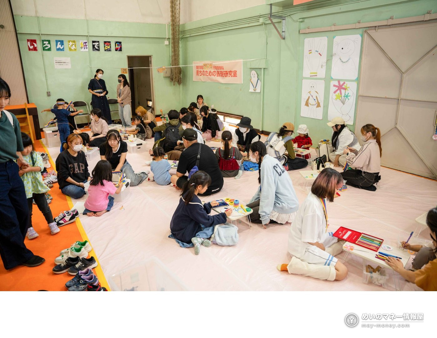 Children and adults sitting on a gym floor making crafts and drawing