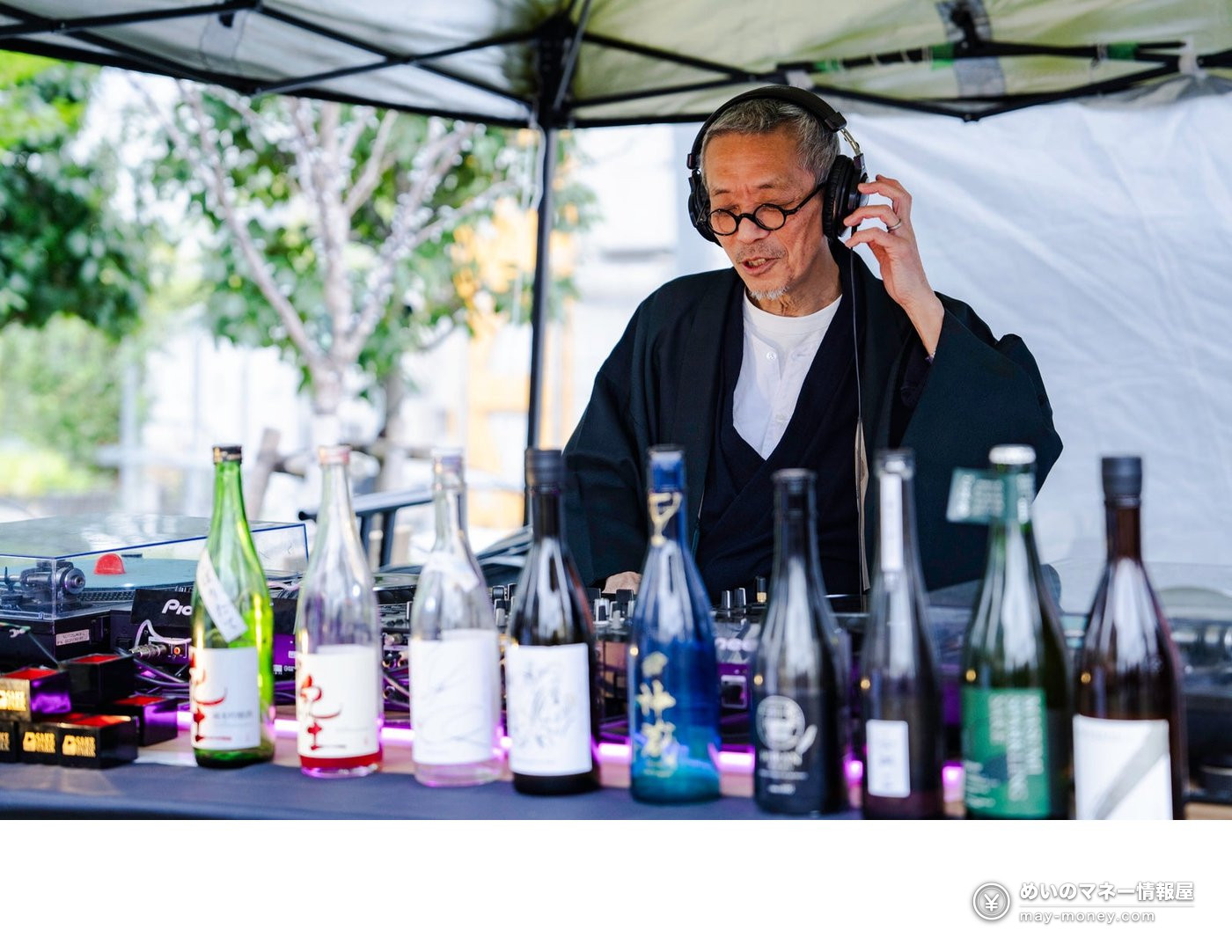 A DJ in headphones playing a set with sake bottles lined up in front