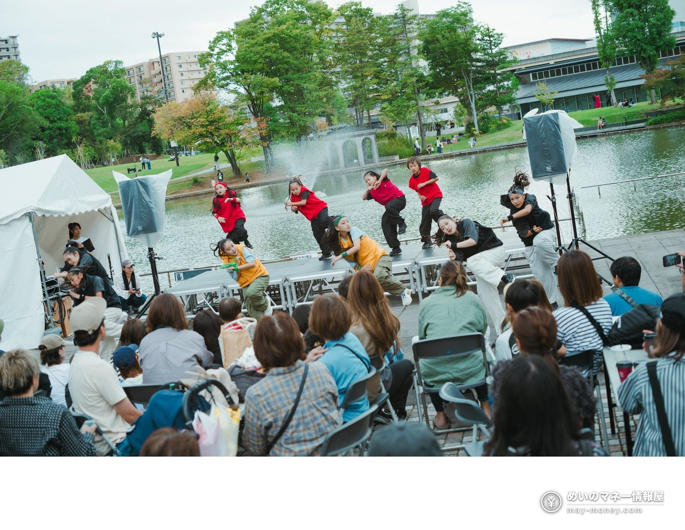 TAMATAMA FESTIVAL 2026: Free Concerts, Food and eSports at Tama Center 7 Children dancing on a stage by the pond in Tama Central Park while an audience watches