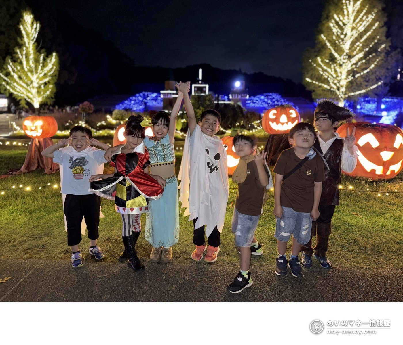 Children in Halloween costumes next to pumpkin decorations