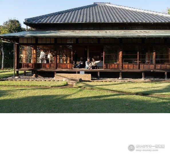 Visitors sitting on the veranda of a traditional Japanese house facing a lawn garden