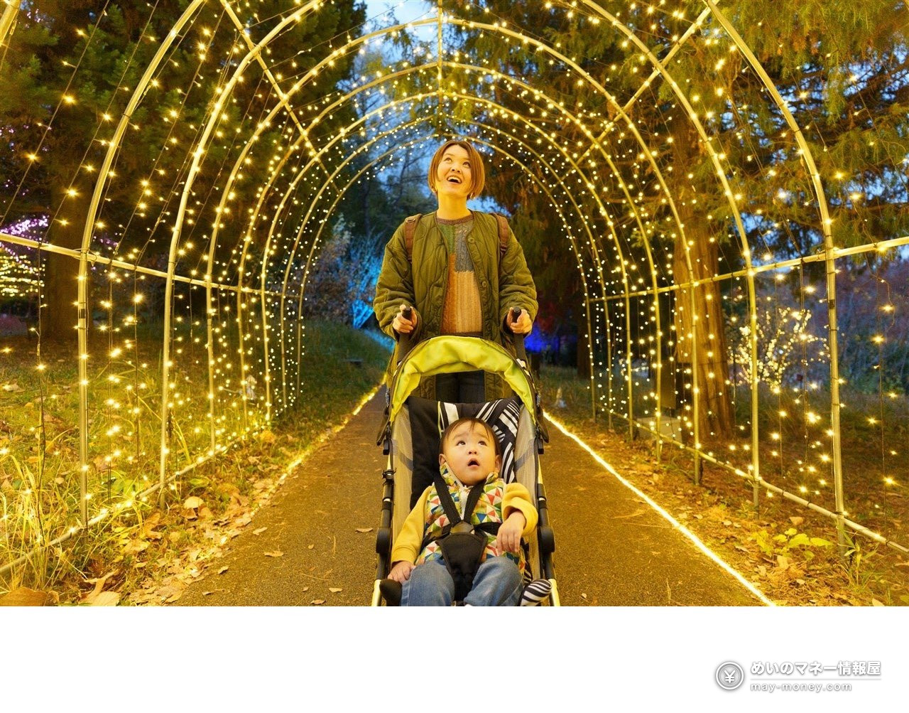 A parent and child with a stroller looking up at a tunnel of lights