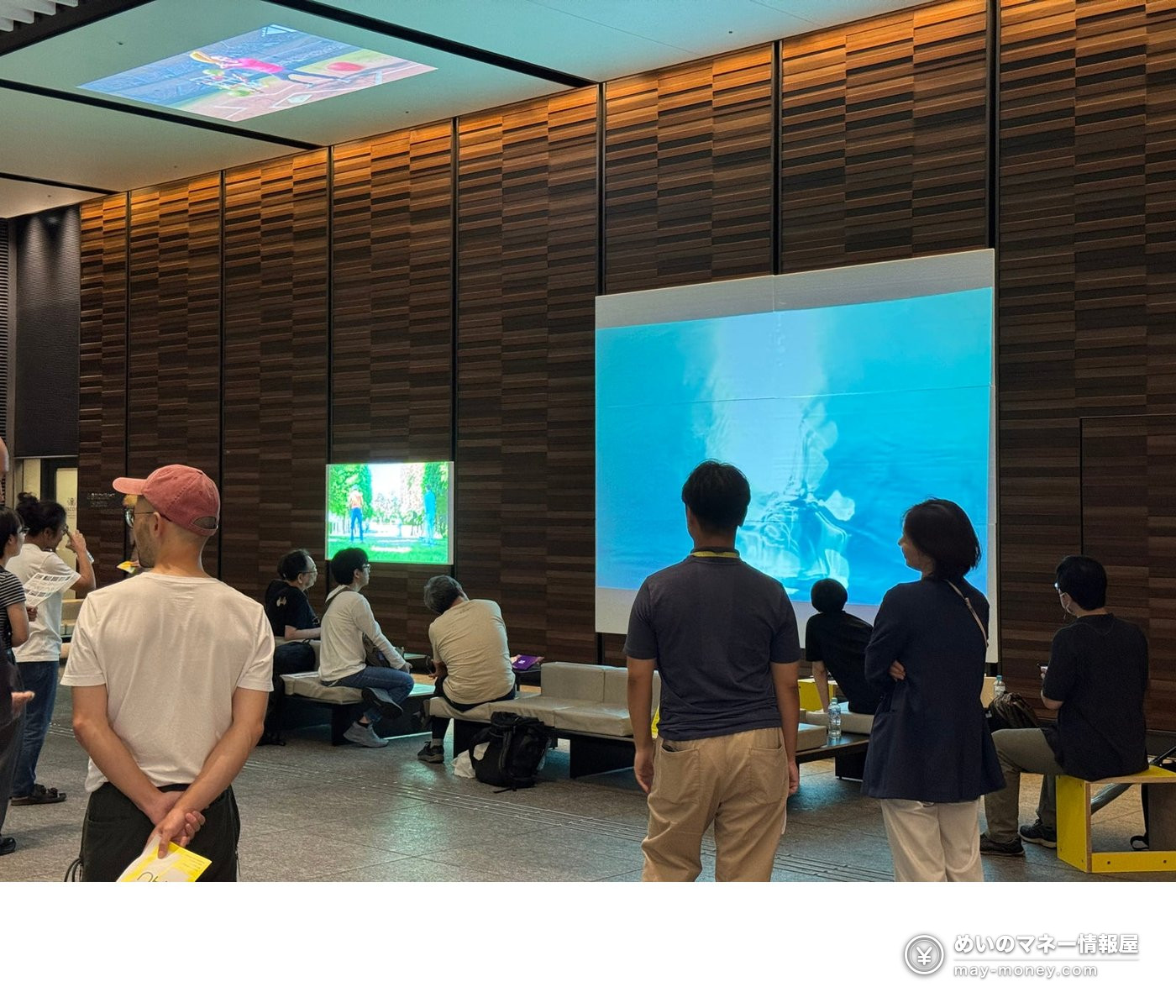 YAU WEEKS: Free Art Walk Across Otemachi, Marunouchi and Yurakucho 8 People watching several projected videos in a wood-paneled lobby at BYOM! vol.1