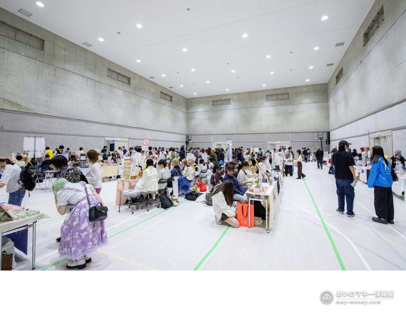 Visitors browsing student goods at market booths inside a gymnasium during the 2025 festival