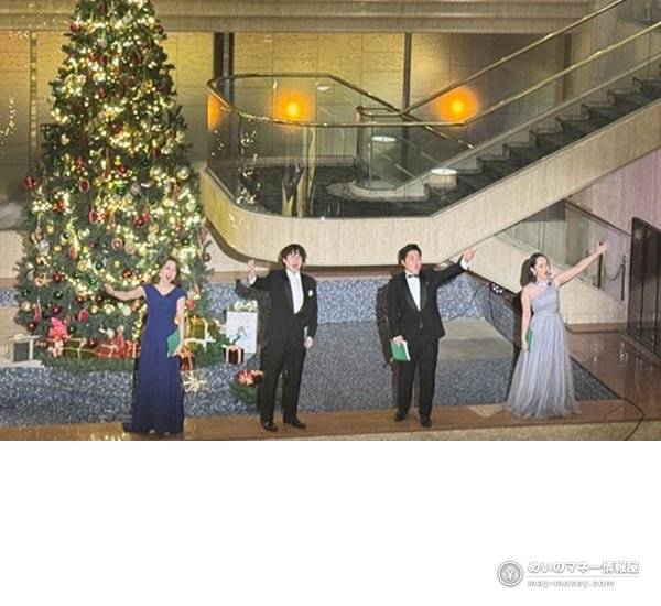 Four singers in formal wear performing in front of the Christmas tree in the hotel lobby