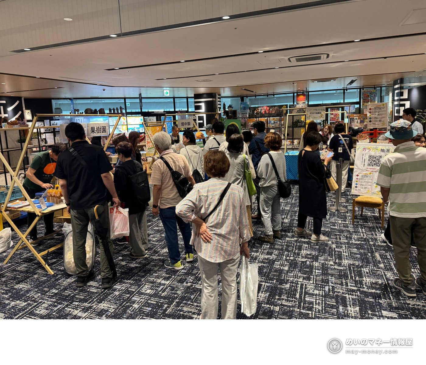 Crowds of visitors at vendor booths in the event space, with a lottery sign