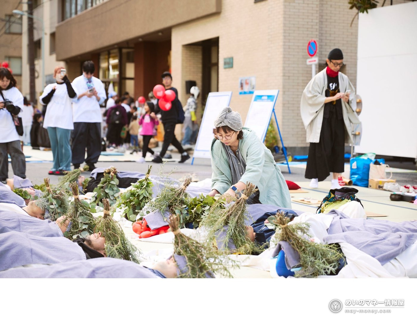 Nandakanda 14: A Free Street Festival on 350 Tatami Mats in Kanda (Nov 3) 6 A woman placing bundles of herbs above the heads of people lying on the street