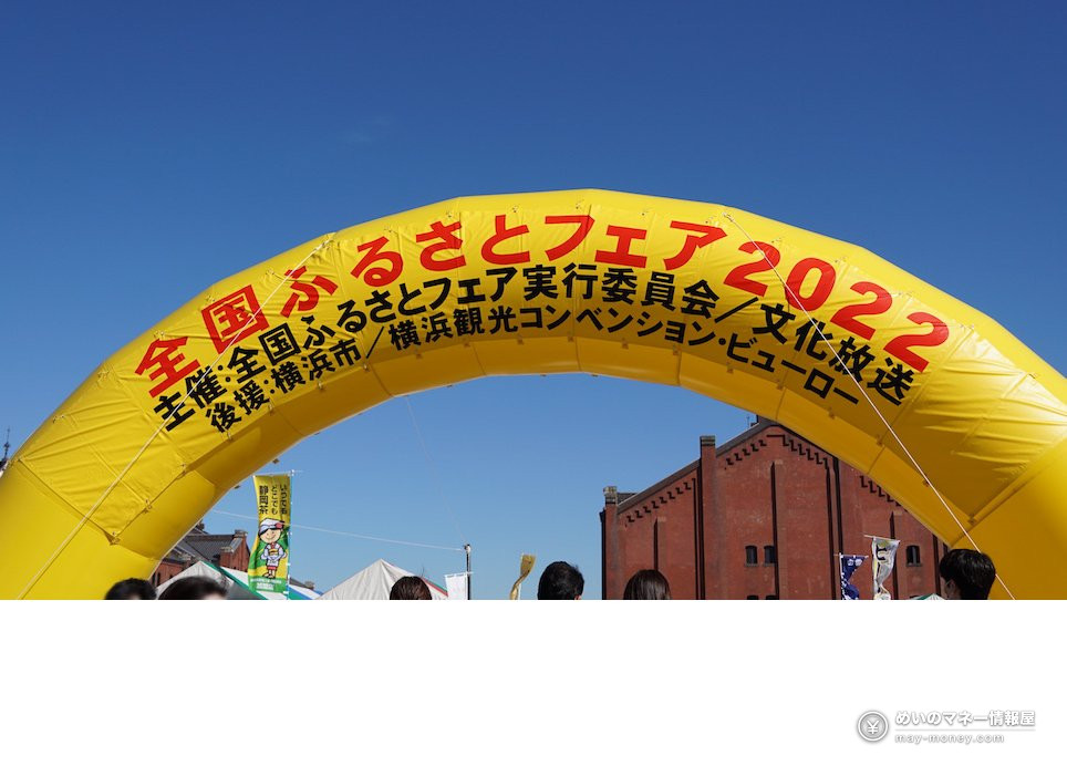 青空の下、赤レンガ倉庫の前に立つ全国ふるさとフェアの黄色いアーチ（2022年開催時）