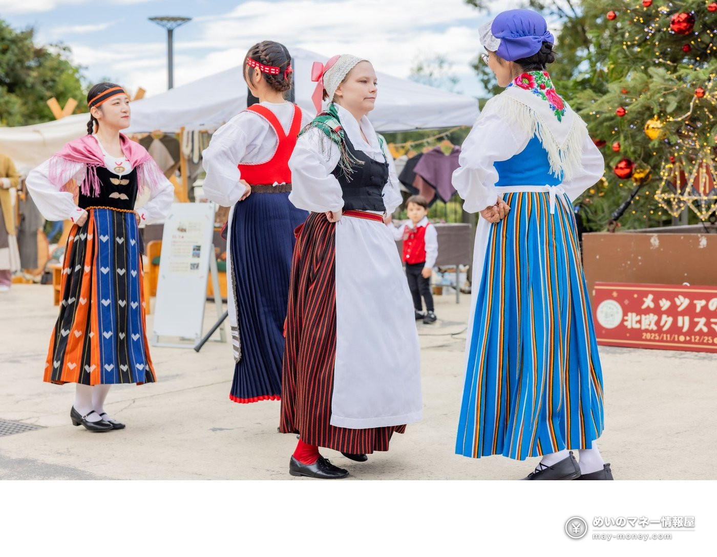 Four women in Nordic folk costumes dancing outdoors