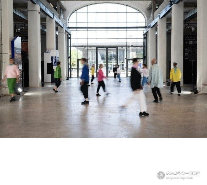 People in colorful clothing walking through a large open hall
