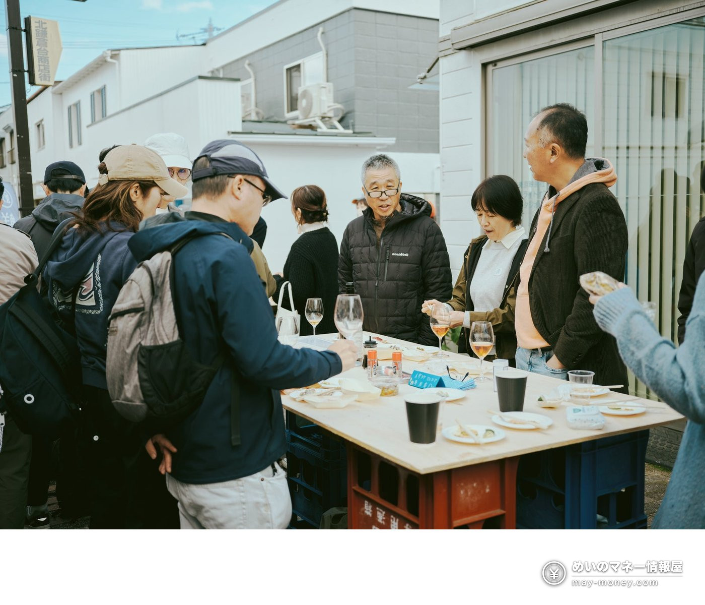 People chatting around an outdoor table with drinks in hand