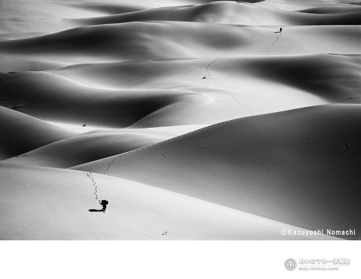 砂丘を歩く二人と、砂の上に長く続く足跡を捉えたモノクロ写真