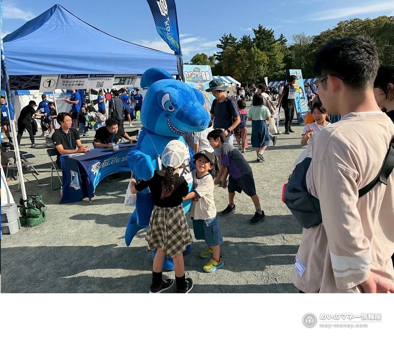 The blue shark mascot greeting children at an outdoor event