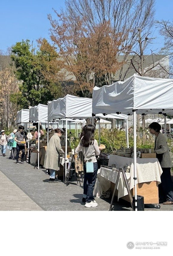 白いテントが並ぶ屋外の市場で買い物を楽しむ人々
