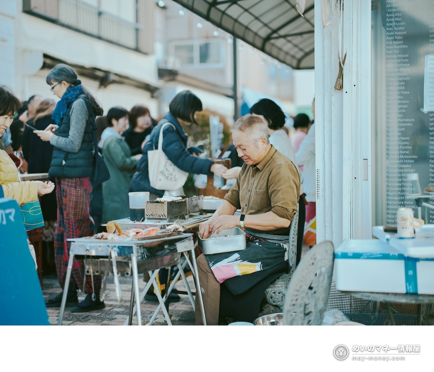 A man cooking on the street as visitors walk past at a market