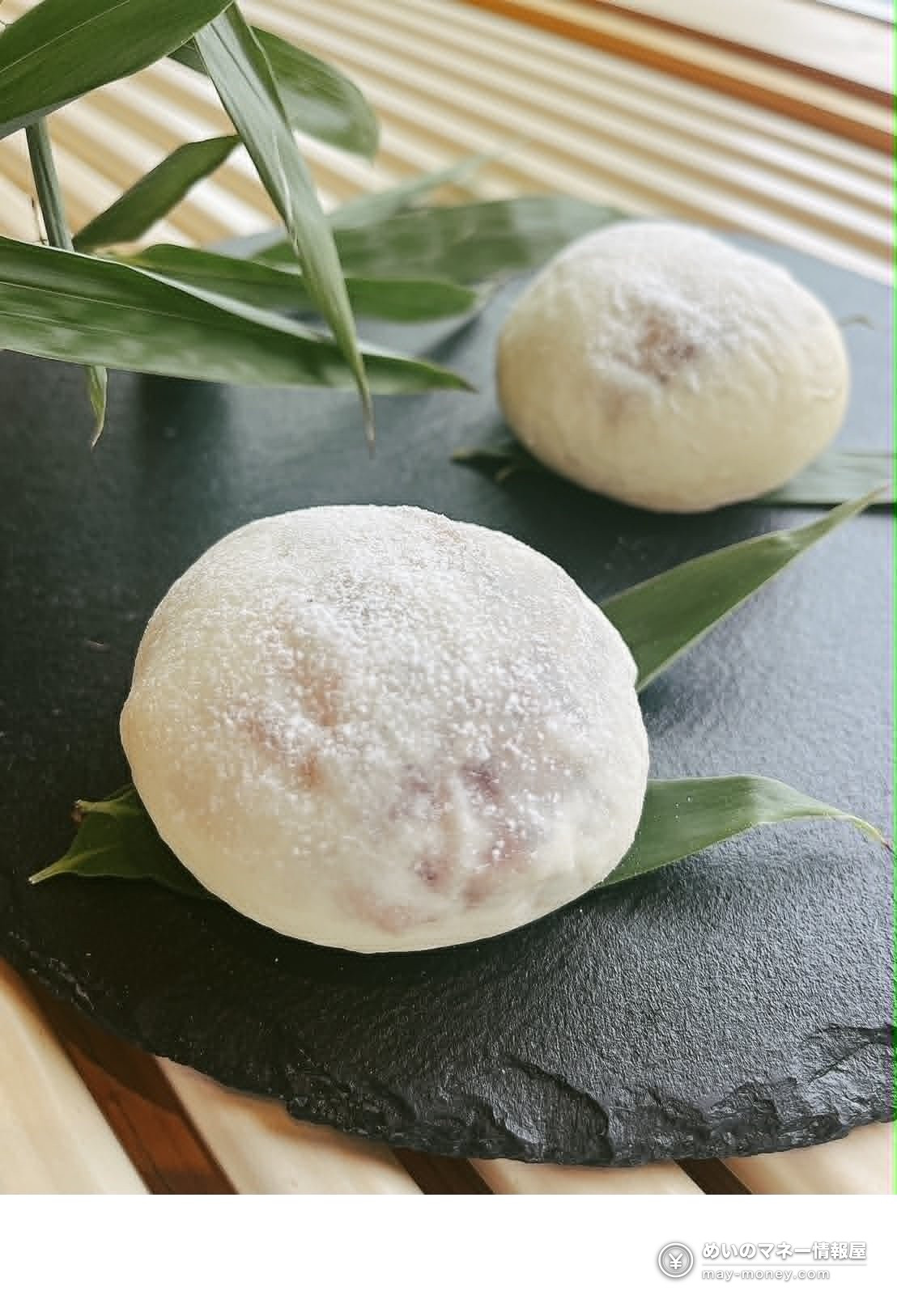 黒い石板に並べられた粉糖付きの白い菓子と笹の葉