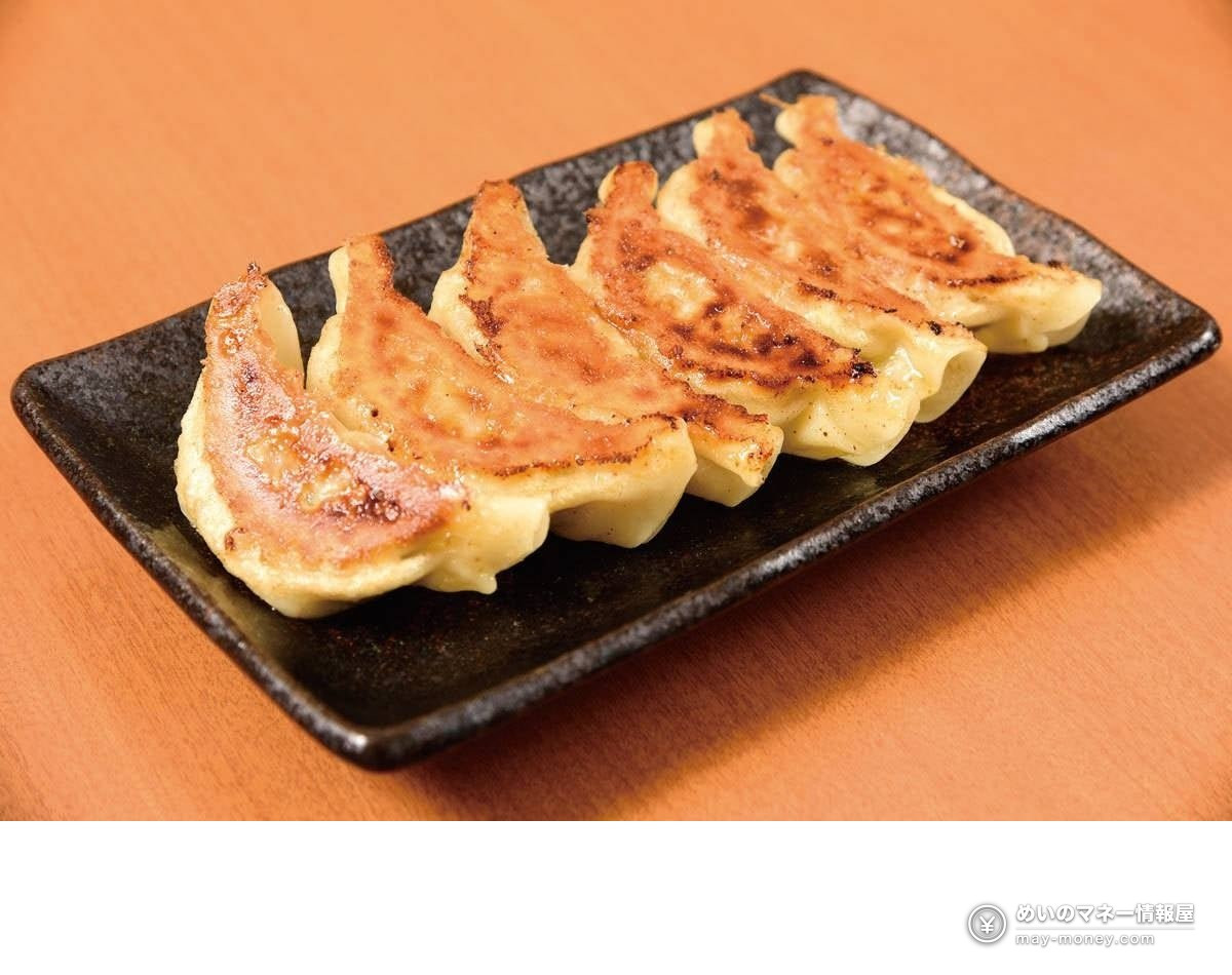 Six pan-fried gyoza lined up on a black square plate