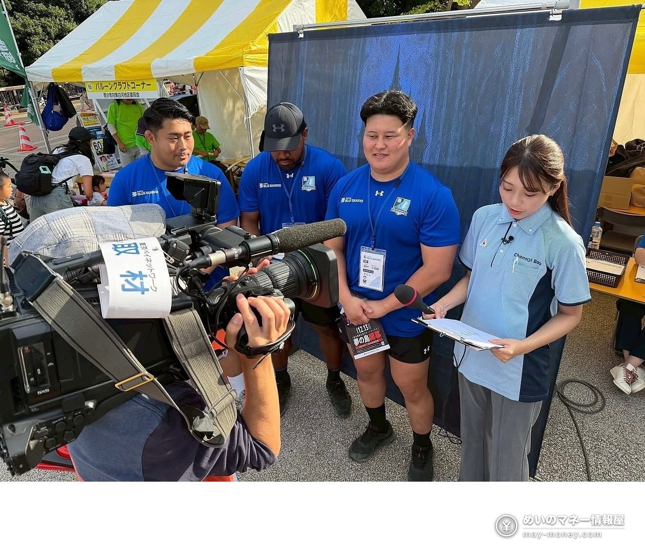 Three Blue Sharks players in blue shirts being interviewed by a reporter in front of a TV camera
