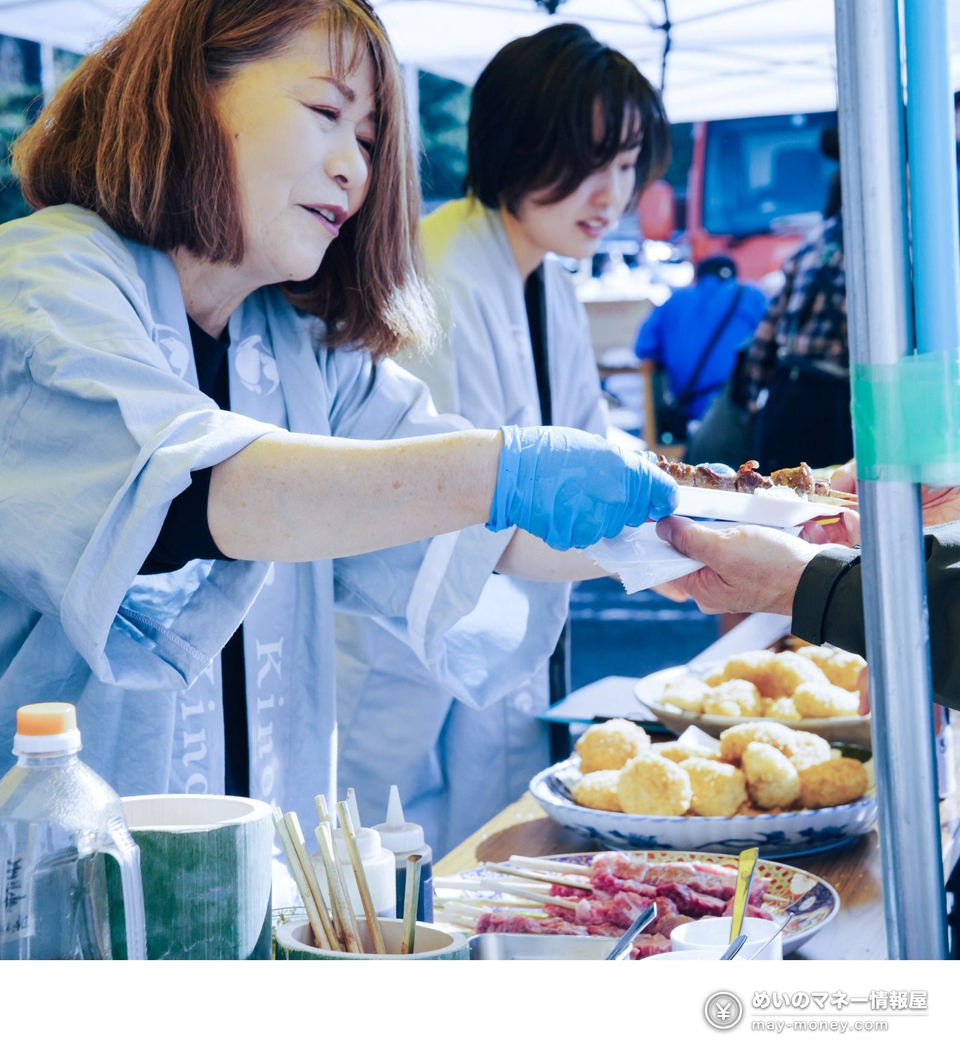 屋台で串料理を来場者に手渡すスタッフの様子