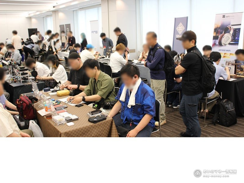 HIFIMANの看板の下、テーブルに並ぶオーディオ機器を来場者が試している展示会場