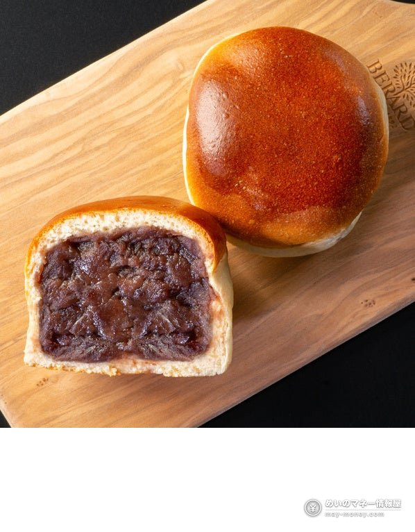 Anpan on a wooden board, one whole and one cut to show the red bean filling